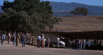 Movie still from “Of Mice and Men” (1992), directed by Gary Sinise – A group of people standing around a barn; Extreme Wide shot, High angle