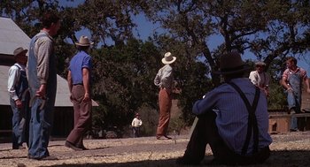 Movie still from “Of Mice and Men” (1992), directed by Gary Sinise – A group of men standing next to each other on a field; Wide shot, Low angle