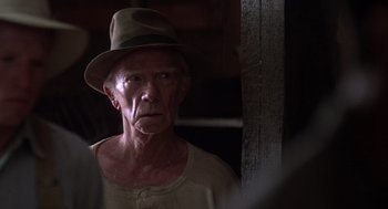 Movie still from “Of Mice and Men” (1992), directed by Gary Sinise – An older man wearing a hat and looking at the camera; Close Up shot, Over the shoulder angle