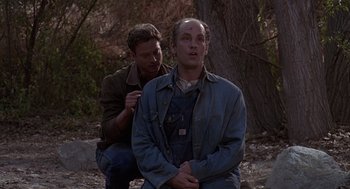 Movie still from “Of Mice and Men” (1992), directed by Gary Sinise – Two men are sitting on the ground in the woods; Medium shot, Over the shoulder angle