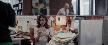Movie still from “Office Christmas Party” (2016), directed by Will Speck – A woman sitting at a desk holding up a cell phone; Medium shot, Over the shoulder angle