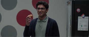 Movie still from “Office Christmas Party” (2016), directed by Will Speck – A man holding a doughnut in his hand; Close Up shot, Over the shoulder angle