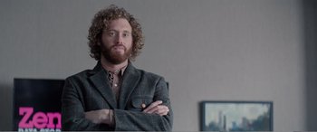 Movie still from “Office Christmas Party” (2016), directed by Will Speck – A man with curly hair wearing a suit and tie; Medium shot, Over the shoulder angle