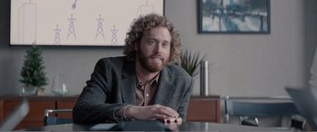 Movie still from “Office Christmas Party” (2016), directed by Will Speck – A man sitting at a table in front of a painting; Medium shot, Over the shoulder angle