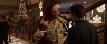 Movie still from “Office Christmas Party” (2016), directed by Will Speck – A man dressed as santa claus with a bunch of money in his chest; Medium shot, Over the shoulder angle