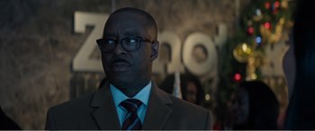 Movie still from “Office Christmas Party” (2016), directed by Will Speck – A man in a suit and tie standing in front of a sign; Close Up shot, Over the shoulder angle