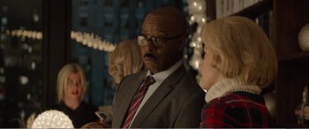 Movie still from “Office Christmas Party” (2016), directed by Will Speck – A man in a suit and tie looking to his left; Medium shot, Over the shoulder angle