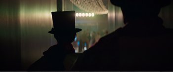 Movie still from “Office Christmas Party” (2016), directed by Will Speck – A man wearing a top hat and a red tie; Medium shot, Over the shoulder angle