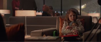 Movie still from “Office Christmas Party” (2016), directed by Will Speck – A little girl sitting at a table in front of a laptop computer; Medium shot, Over the shoulder angle