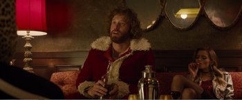 Movie still from “Office Christmas Party” (2016), directed by Will Speck – A man in a red coat holding a wine glass; Medium shot, Over the shoulder angle