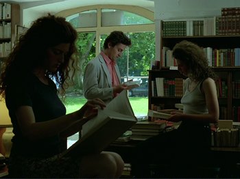 Movie still from “Oh, Woe Is Me” (1993), directed by Jean-Luc Godard – Three people sitting at a table looking at papers; Medium shot, Low angle