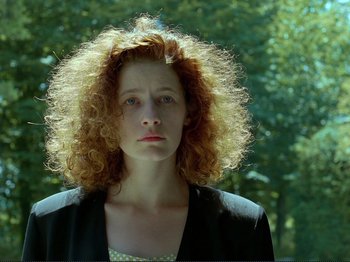 Movie still from “Oh, Woe Is Me” (1993), directed by Jean-Luc Godard – A person with curly red hair; Close Up shot, Low angle