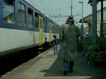 Movie still from “Oh, Woe Is Me” (1993), directed by Jean-Luc Godard – A man and a child walking down a train platform; Wide shot, Over the shoulder angle