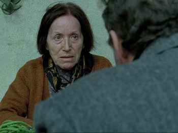 Movie still from “Oh, Woe Is Me” (1993), directed by Jean-Luc Godard – An older woman sitting in front of an older man in front of a mirror; Close Up shot, Over the shoulder angle