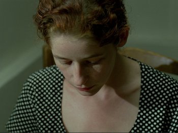 Movie still from “Oh, Woe Is Me” (1993), directed by Jean-Luc Godard – A person sitting in a chair; Close Up shot, High angle