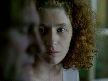 Movie still from “Oh, Woe Is Me” (1993), directed by Jean-Luc Godard – A person with curly red hair; Close Up shot, Over the shoulder angle