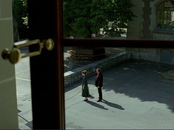 Movie still from “Oh, Woe Is Me” (1993), directed by Jean-Luc Godard – A man and a woman standing on a sidewalk; Extreme Wide shot, High angle