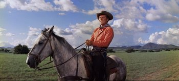 Movie still from “Oklahoma!” (1955), directed by Fred Zinnemann – A man in a cowboy hat is riding a horse; Medium shot, Low angle
