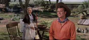 Movie still from “Oklahoma!” (1955), directed by Fred Zinnemann – An older woman and a young man in a cowboy hat; Medium shot, Low angle