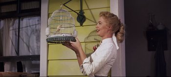 Movie still from “Oklahoma!” (1955), directed by Fred Zinnemann – A woman holding a bird in a bird cage; Medium shot, Low angle