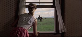 Movie still from “Oklahoma!” (1955), directed by Fred Zinnemann – A woman looking out a window at a horse drawn carriage; Wide shot, Low angle