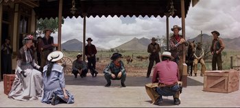 Movie still from “Oklahoma!” (1955), directed by Fred Zinnemann – A man kneeling down in front of a group of people; Wide shot, Low angle
