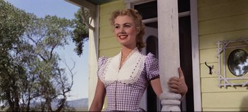 Movie still from “Oklahoma!” (1955), directed by Fred Zinnemann – A woman standing on the porch of a house; Medium shot, Low angle