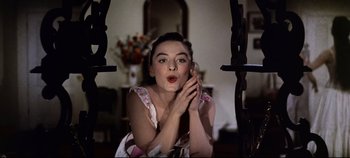 Movie still from “Oklahoma!” (1955), directed by Fred Zinnemann – A woman is talking on a phone while sitting on a swing; Close Up shot, Low angle