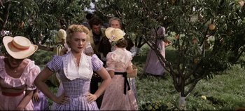 Movie still from “Oklahoma!” (1955), directed by Fred Zinnemann – A group of people standing next to each other in a field; Medium shot, Over the shoulder angle