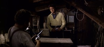 Movie still from “Oklahoma!” (1955), directed by Fred Zinnemann – A man standing in front of a table holding a cell phone; Medium shot, Over the shoulder angle