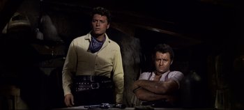 Movie still from “Oklahoma!” (1955), directed by Fred Zinnemann – A man and a woman standing next to each other; Medium shot, Low angle