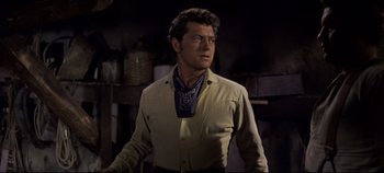 Movie still from “Oklahoma!” (1955), directed by Fred Zinnemann – A man wearing a cowboy outfit and a bandana; Medium shot, Over the shoulder angle