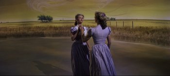 Movie still from “Oklahoma!” (1955), directed by Fred Zinnemann – A couple of women standing next to each other on top of a field; Wide shot, Low angle