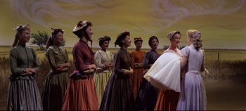 Movie still from “Oklahoma!” (1955), directed by Fred Zinnemann – A group of women dressed in period clothing; Medium shot, Low angle