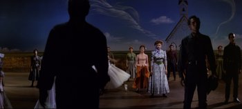 Movie still from “Oklahoma!” (1955), directed by Fred Zinnemann – A group of people standing in front of a sky background; Wide shot, Low angle