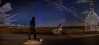 Movie still from “Oklahoma!” (1955), directed by Fred Zinnemann – A couple of people that are standing in the dirt; Wide shot, Low angle