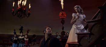 Movie still from “Oklahoma!” (1955), directed by Fred Zinnemann – A man and a woman are standing in front of a fire; Wide shot, Low angle