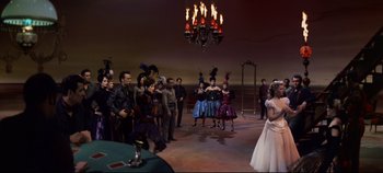 Movie still from “Oklahoma!” (1955), directed by Fred Zinnemann – A group of people standing in a room; Wide shot, High angle