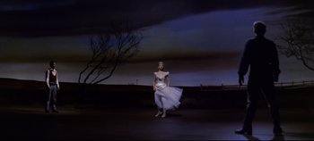 Movie still from “Oklahoma!” (1955), directed by Fred Zinnemann – A woman in a white dress standing in front of a tree; Wide shot, Low angle