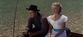 Movie still from “Oklahoma!” (1955), directed by Fred Zinnemann – A man and a woman sitting next to each other on a bench; Medium shot, Low angle