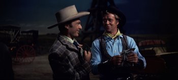 Movie still from “Oklahoma!” (1955), directed by Fred Zinnemann – Two men dressed up in western clothing and hats; Medium shot, Over the shoulder angle
