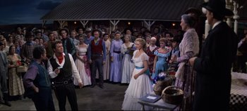 Movie still from “Oklahoma!” (1955), directed by Fred Zinnemann – A group of people standing in front of each other; Wide shot, Over the shoulder angle