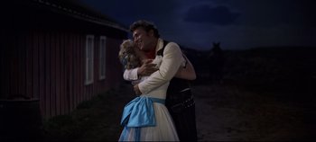 Movie still from “Oklahoma!” (1955), directed by Fred Zinnemann – A man and a woman embracing each other; Medium shot, Low angle