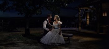 Movie still from “Oklahoma!” (1955), directed by Fred Zinnemann – A man and a woman sitting on a park bench; Wide shot, High angle