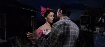 Movie still from “Oklahoma!” (1955), directed by Fred Zinnemann – A man and a woman are standing next to each other; Medium shot, Over the shoulder angle