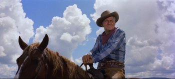 Movie still from “Oklahoma!” (1955), directed by Fred Zinnemann – A man in a cowboy hat is sitting on a horse; Medium shot, Low angle