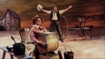 Movie still from “Oklahoma!” (1999), directed by Trevor Nunn – A man and a woman are standing next to each other; Wide shot, High angle