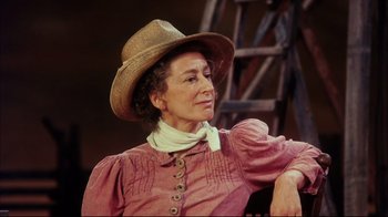 Movie still from “Oklahoma!” (1999), directed by Trevor Nunn – An older woman wearing a hat and a pink dress; Close Up shot, Low angle