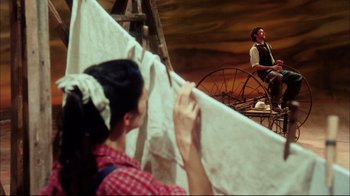 Movie still from “Oklahoma!” (1999), directed by Trevor Nunn – A man and a woman are standing in front of a wagon; Wide shot, Low angle
