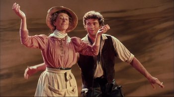 Movie still from “Oklahoma!” (1999), directed by Trevor Nunn – A man and a woman standing next to each other; Medium shot, Low angle